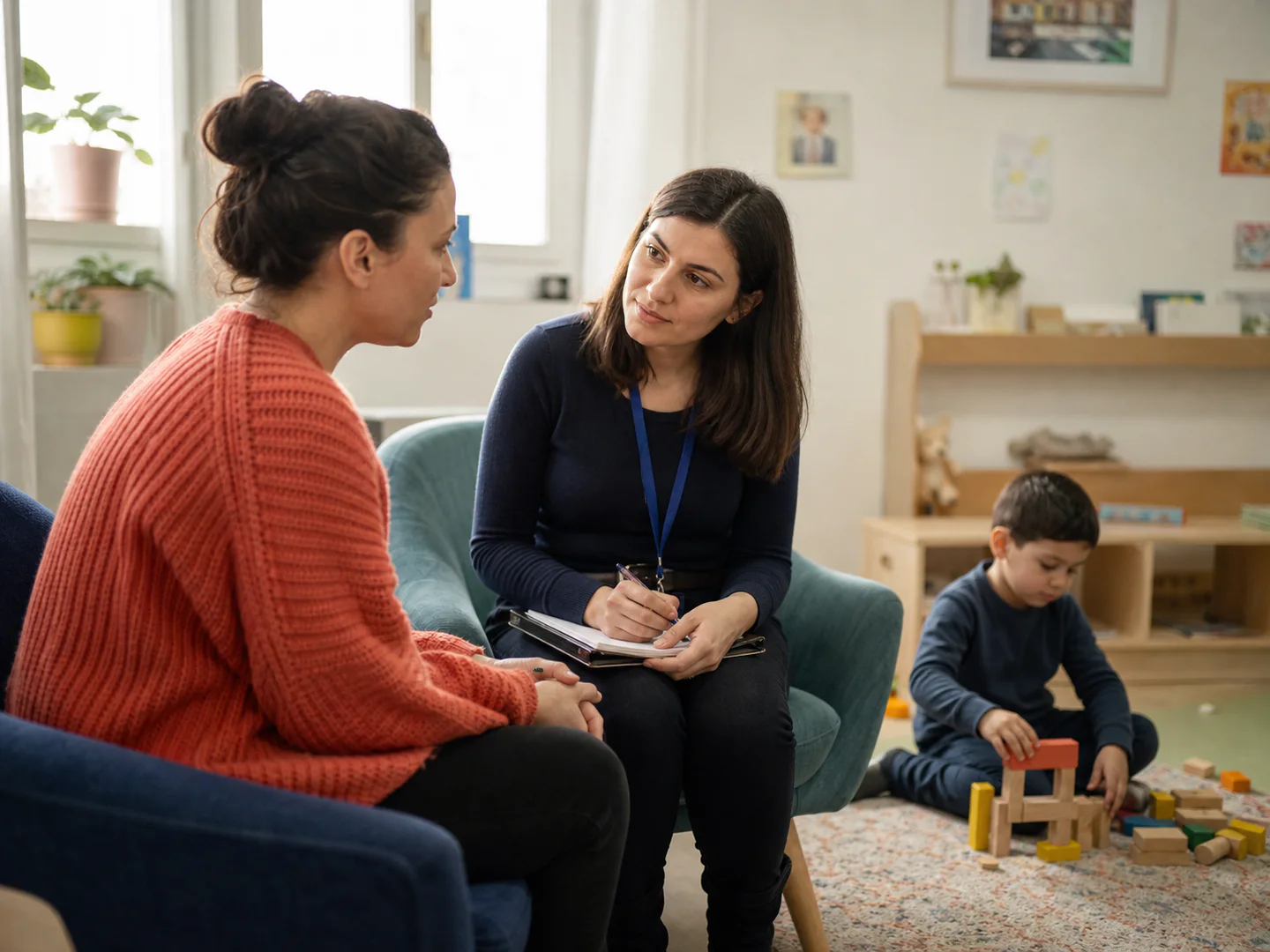 Un părinte discută cu un specialist în timp ce copilul se joacă